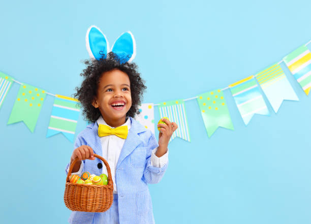istock Cheerful black child laughing happily in blue studio with Easter basket in hand 1308236313
