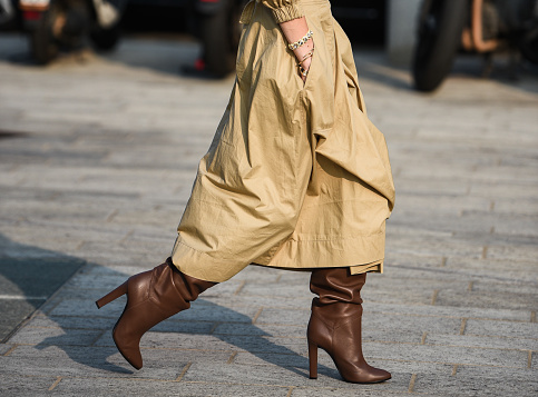 Elegante atuendo en detalle, mujeres con abrigo crema y botas marrones photo