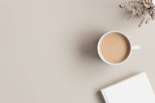 istock White book, cup of a coffee and a lavender on a beige table.  Flat lay with blank copy space. 1308237435