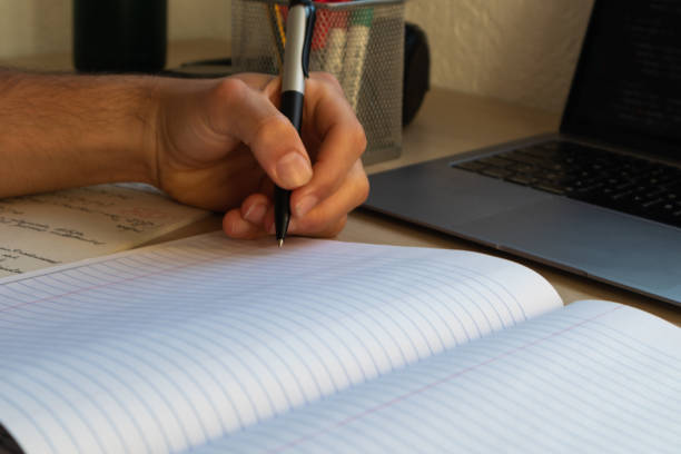 istock side view of high school or college student studying and writing in a notebook on a desk with a laptop 1308238473