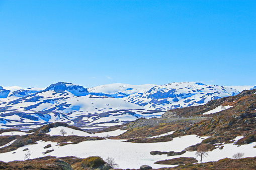 Highland mountain valley with melting snow under clear blue sky, beautiful arctic polar Norway landscape