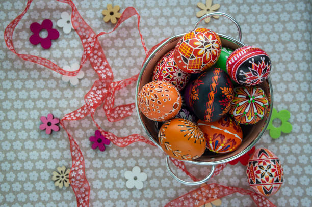 istock Homemade handmade painted Easter eggs in decorative old pink color tin on flowered tablecloth with decorative flowers and ribbon 1308240829