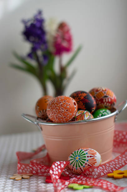 istock Homemade handmade painted Easter eggs in decorative old pink color tin on flowered tablecloth with flowering hyacinth flowers 1308240837