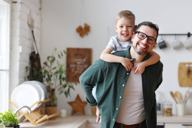 joyful father piggybacking happy son in kitchen - 16312 imagens e fotografias de stock