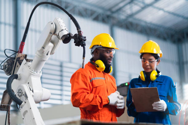 istock engineer cooperation male and female technician maintenance control relay robot arm system welding with tablet laptop to control quality operate process work heavy industry 4.0 manufacturing factory 1308247440