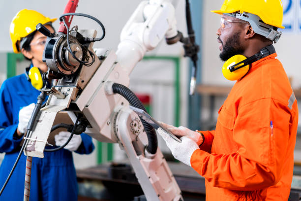 istock engineer cooperation male and female technician maintenance control relay robot arm system welding with tablet laptop to control quality operate process work heavy industry 4.0 manufacturing factory 1308247450
