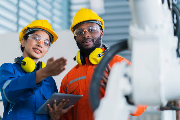 istock engineer cooperation male and female technician maintenance control relay robot arm system welding with tablet laptop to control quality operate process work heavy industry 4.0 manufacturing factory 1308247493