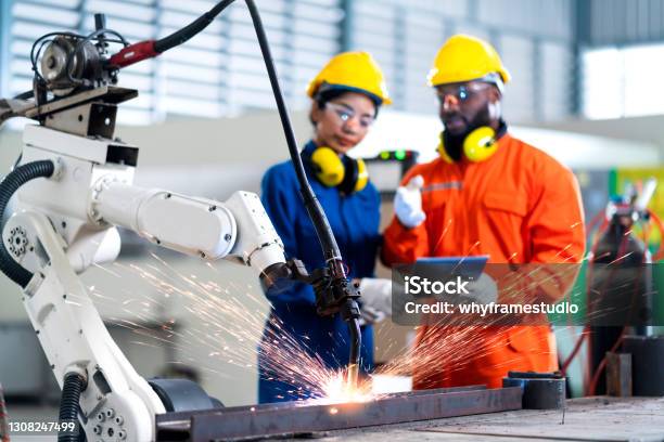 Engineer Cooperation Male And Female Technician Maintenance Control Relay Robot Arm System Welding With Tablet Laptop To Control Quality Operate Process Work Heavy Industry 40 Manufacturing Factory Stock Photo - Download Image Now