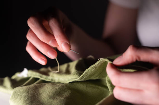 female hands with sewing needle and thread mending clothes - manual worker sewing women tailor imagens e fotografias de stock