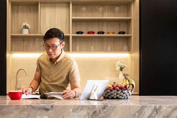 Photo of Asian enjoy his coffee and reading magazine