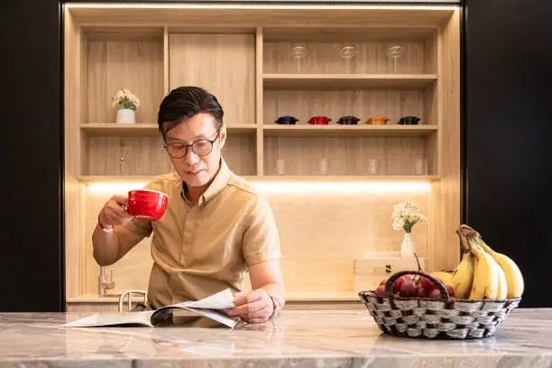 Photo of Asian enjoy his coffee and reading magazine