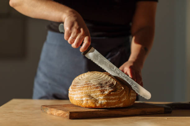 istock Woman Cutting Sourdough Bread with Knife on Board 1308252075