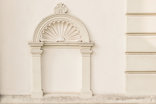 Decorative arch and semi vault above niche with classic pillars. Architectural stucco detail of old European buildingin Prague. Elegant masonry facade decor in beige color, no people, front view.