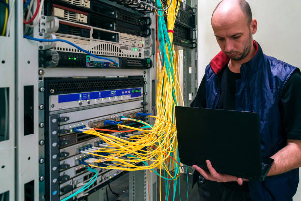 istock The system administrator with a laptop is in the server room. A man sets up a central router in a datacenter. Configuring server hardware. 1308255166