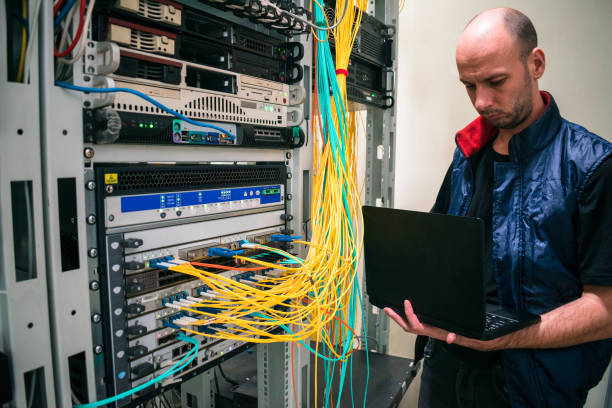 istock The system administrator with a laptop is in the server room. A man sets up a central router in a datacenter. Configuring server hardware. 1308255168
