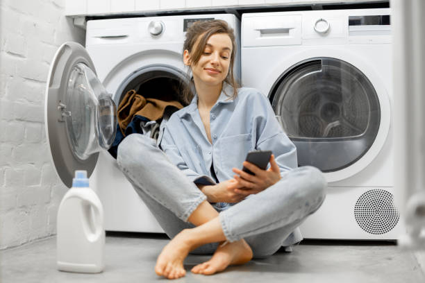 istock Relaxed woman with a smartphone in the laundry room 1308255573