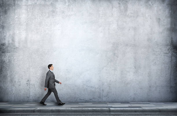 istock Businessman Walking On Sidewalk Next To Concrete W 1308264801
