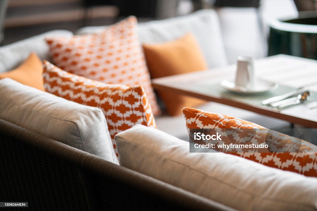 close up colorful soft pillows cushion arrange on nature material dining chair with blur patio area background interior design concept Furniture Stock Photo