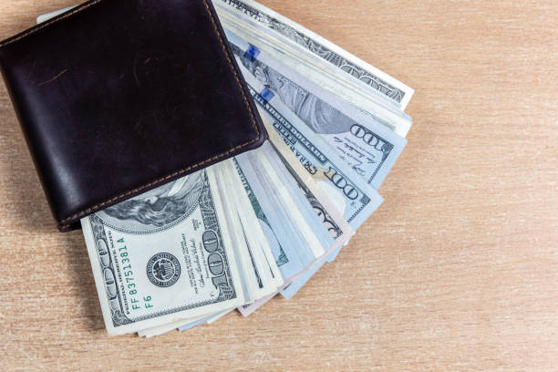 istock dollar bills in a brown wallet on a wooden background. 1308265374