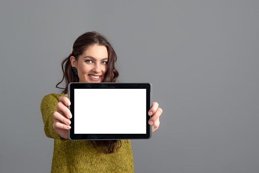 emotional young woman showing tablet computer with empty touch screen with copy space, isolated on gray background