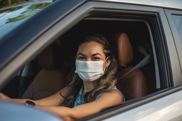 istock Woman driving a car wearing mask 1308267692