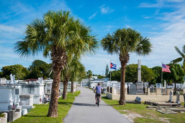 Key West, Florida, USA - January 17, 2015: A man rides his bike through the historic Key West Cemetery, established in 1847 after a hurricane washed bodies out from their previous location.