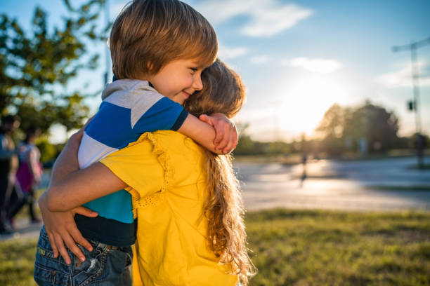 Smiling loving young boy and girl hugging. Portrait of them outside.