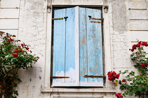 Closed wooden shutters of blue color on the window of the old house