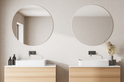 Modern bathroom with white walls, two sink with round mirrors and left window light. 3d rendering