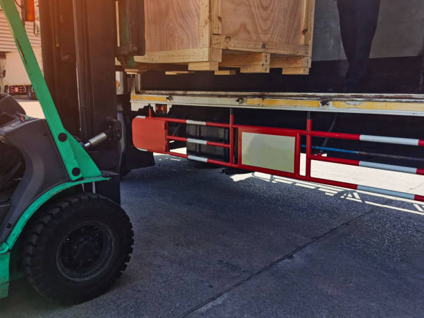 istock Worker driving forklift loading shipment carton boxes goods on wooden pallet at loading dock from container truck to warehouse cargo storage in freight logistics, transportation industrial, delivery 1308275518