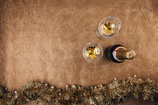 Wine glasses, bunch of confetti and champagne bottle on brown background. Flat lay concept.