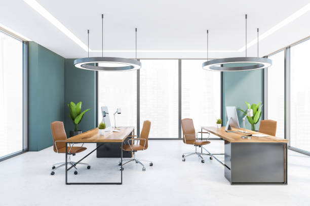 istock Office consulting room with wooden tables and computers, armchairs, windows 1308275992