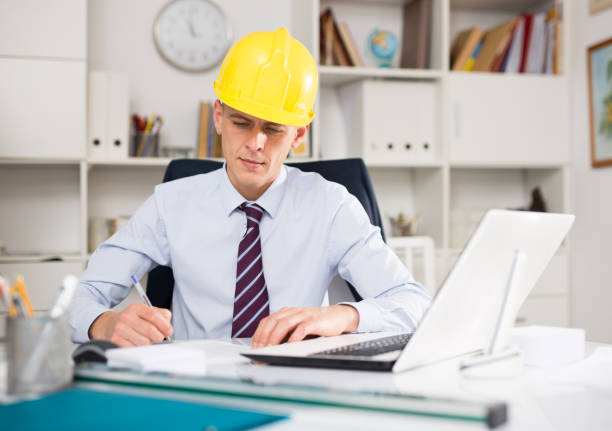 istock Male engineer works at a computer and takes important notes 1308278788
