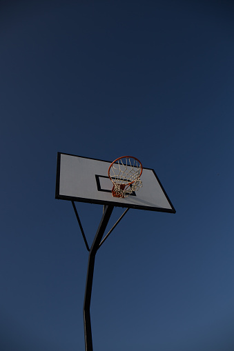 close-up of a basketball basket, rectangular white board with black lines and orange basket with net