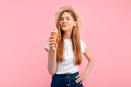Attractive young woman having ice cream on isolated pink background, summer concept