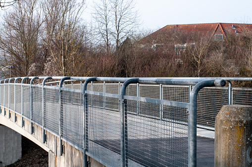 a bannister of a footbridge over a street with metal grid