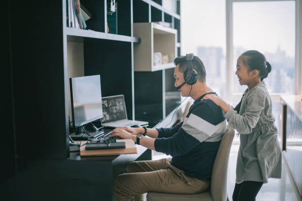 mischief asian chinese daughter distracting playing disturbing her father who working from home routine with headset videocall with his colleague coworking
