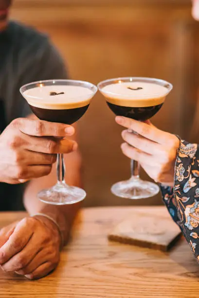 Photo of Two servings of espresso coffee cocktail in tall martini glasses decorated with coffee beans.