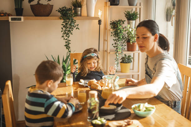 istock Mother and her two kids sitting at table and eating breakfast 1308287925