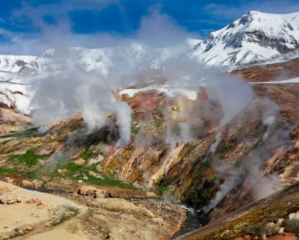 May landscape with columns of steam and gases in the Valley of Geysers. Active volcanic activity and thermal fields in the floodplain of the Geysernaya River in Kamchatka.
