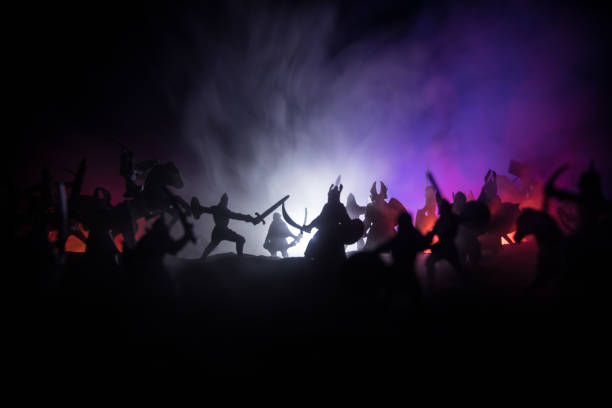 istock Medieval battle scene with cavalry and infantry. Silhouettes of figures as separate objects, fight between warriors on sunset foggy background. 1308288066