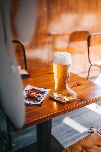 Beer glass boot with delicious spanish iberian ham snacks on a wooden table