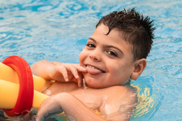 istock disabled boy with a mischievous face, swimming with a float in a pool. 1308290315