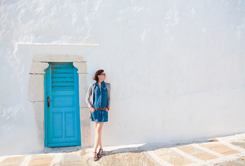 Tourist in Greece, on Mykonos island, stranding against a wall of old church.