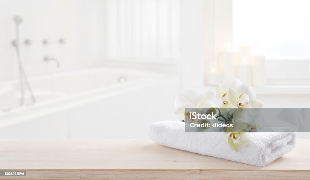 Towel and orchid flowers on wooden table with copy space Bathroom Stock Photo