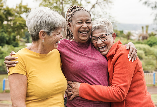 Felices mujeres mayores multirraciales divirtiéndose juntas al aire libre - Ancianos generaciones personas abrazándose en el parque photo
