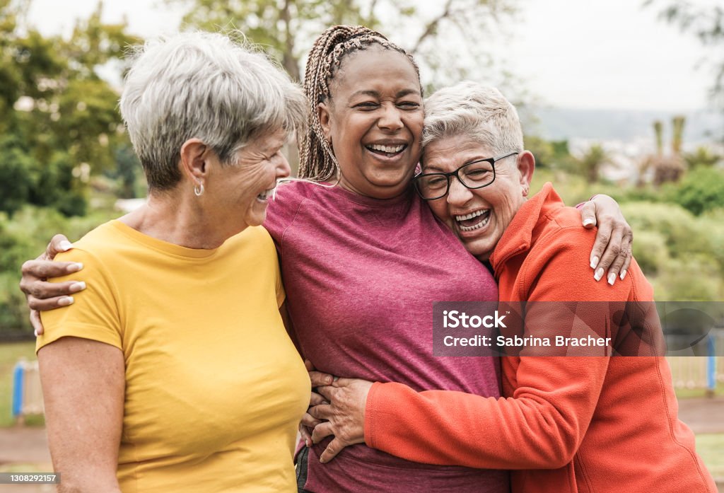 Happy multiracial senior women having fun together outdoor - Elderly generation people hugging each other at park Senior Adult Stock Photo