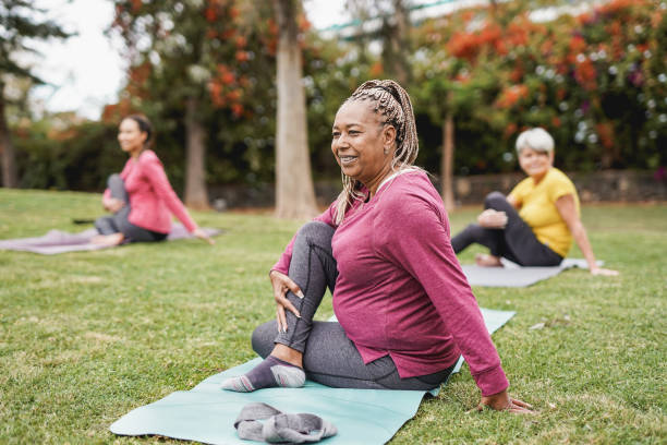 donne multirazziali che fanno esercizio yoga con distanza sociale per l'epidemia di coronavirus al parco all'aperto - stile di vita sano e concetto di sport - ambientazione esterna foto e immagini stock