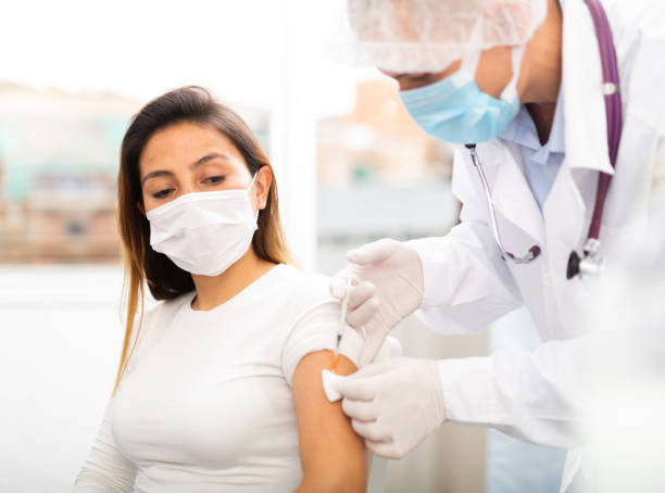 istock doctor in protective face mask vaccinates woman 1308294891