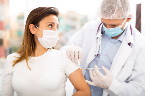 istock doctor in protective face mask vaccinates woman 1308294910